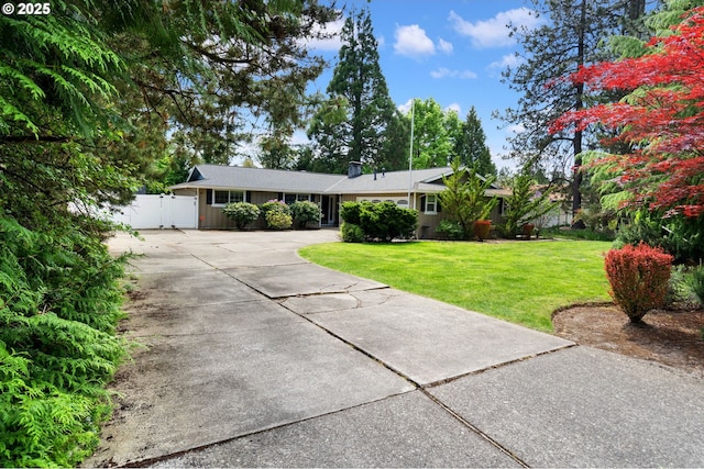 single story home featuring a gate, a front lawn, fence, and concrete driveway