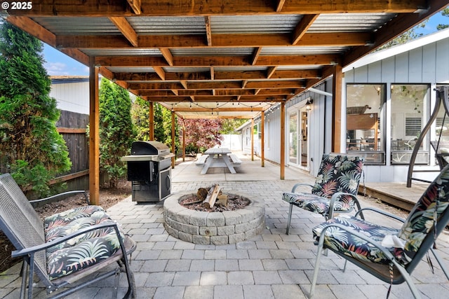 view of patio featuring an outdoor fire pit, fence, and a grill