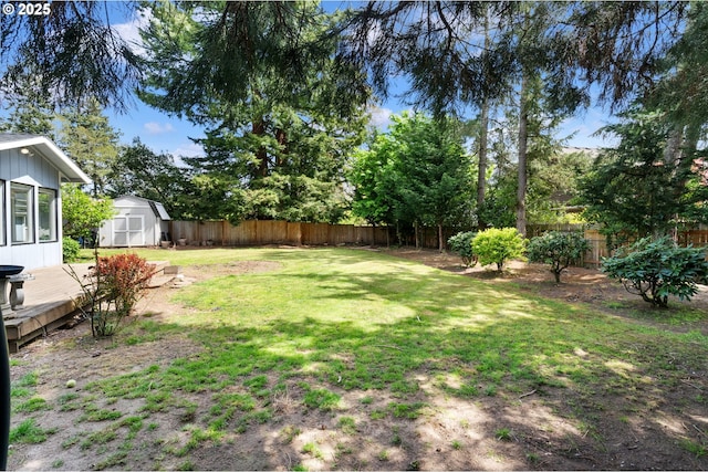 view of yard with an outdoor structure, a deck, a shed, and a fenced backyard
