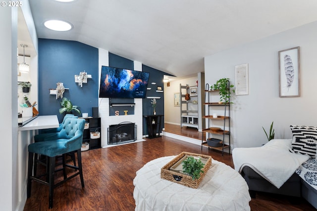 living room with vaulted ceiling, a fireplace with flush hearth, and wood finished floors