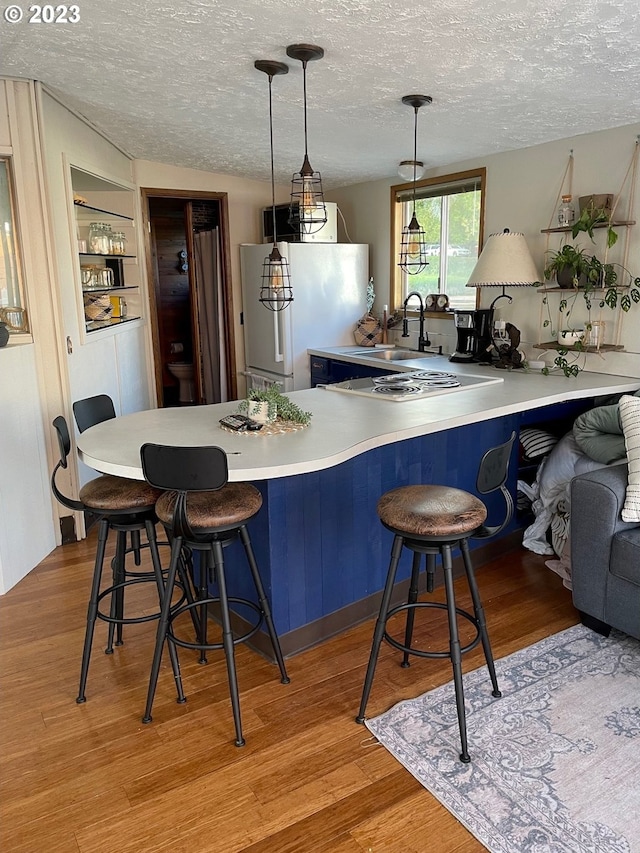 kitchen featuring hanging light fixtures, white refrigerator, a kitchen bar, built in shelves, and kitchen peninsula