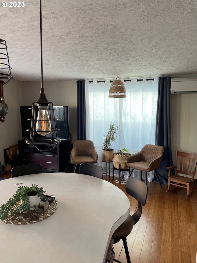 dining room featuring a wall mounted air conditioner, hardwood / wood-style floors, and a textured ceiling