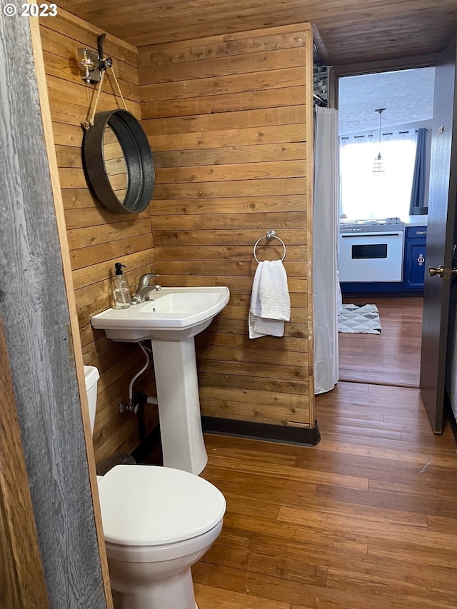 bathroom with sink, wood ceiling, hardwood / wood-style flooring, toilet, and wood walls