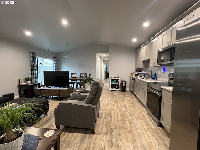 kitchen featuring light wood finished floors, open floor plan, recessed lighting, lofted ceiling, and appliances with stainless steel finishes