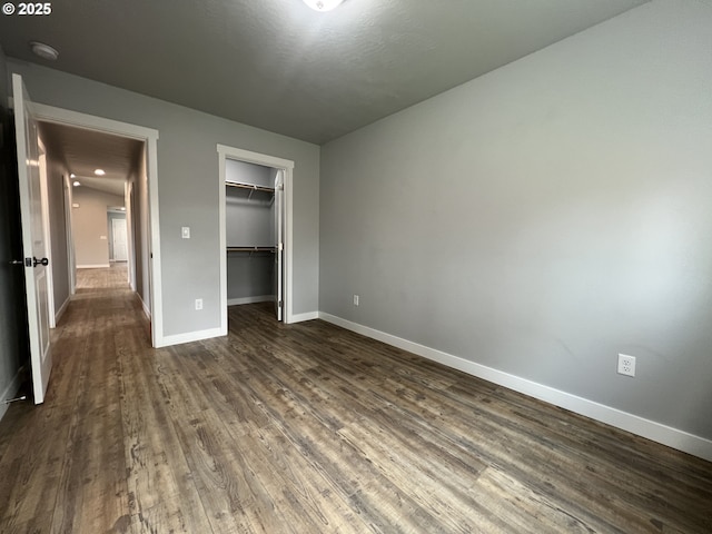 unfurnished bedroom with dark wood-type flooring, a closet, and baseboards