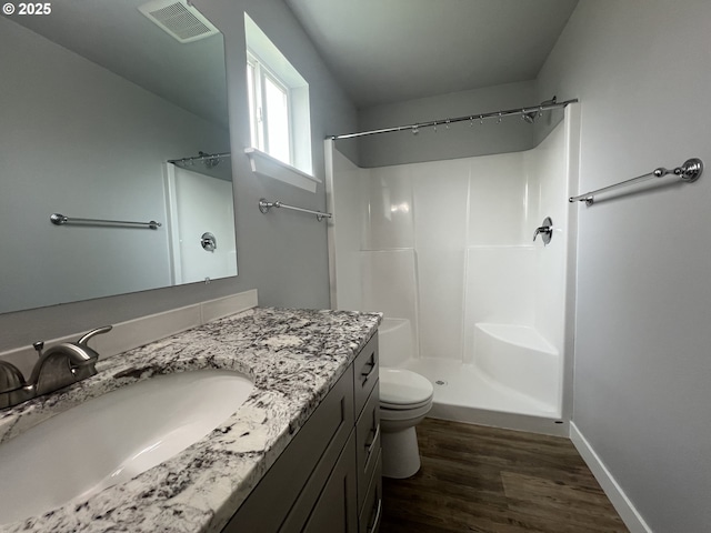 full bathroom featuring wood finished floors, visible vents, toilet, vanity, and walk in shower