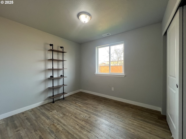 unfurnished bedroom featuring baseboards, dark wood-type flooring, visible vents, and a closet