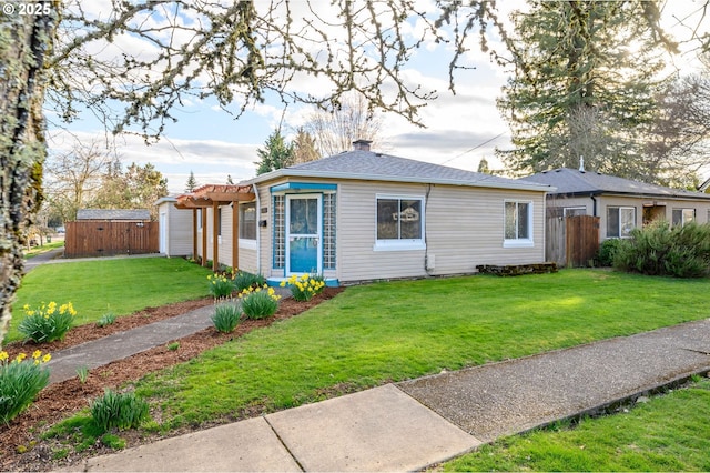 view of front facade with a pergola, fence, a storage shed, an outdoor structure, and a front yard