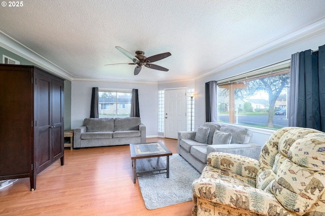 living room featuring a wealth of natural light, visible vents, light wood-style floors, and ornamental molding