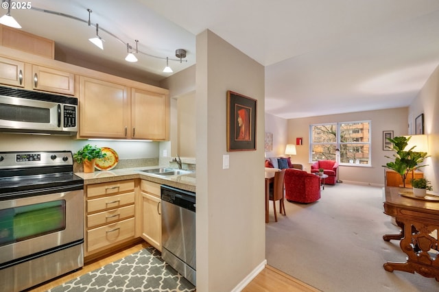 kitchen featuring light carpet, light brown cabinetry, stainless steel appliances, and sink