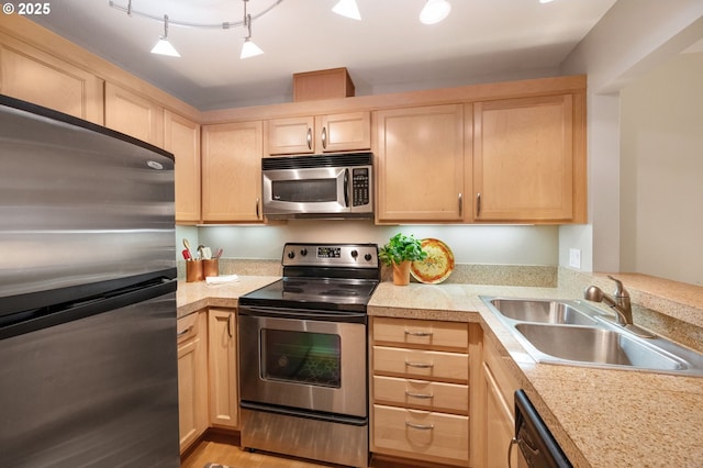 kitchen with light brown cabinetry, stainless steel appliances, track lighting, and sink