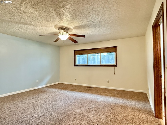 empty room featuring carpet, a ceiling fan, visible vents, baseboards, and a textured ceiling