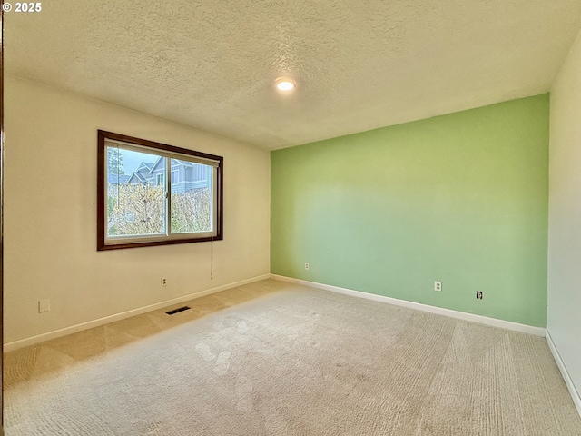 unfurnished room with visible vents, a textured ceiling, baseboards, and carpet floors