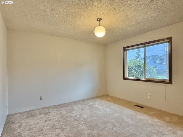 empty room with visible vents, carpet flooring, and a textured ceiling