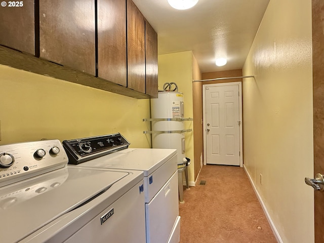 clothes washing area with strapped water heater, baseboards, cabinet space, water heater, and washer and dryer