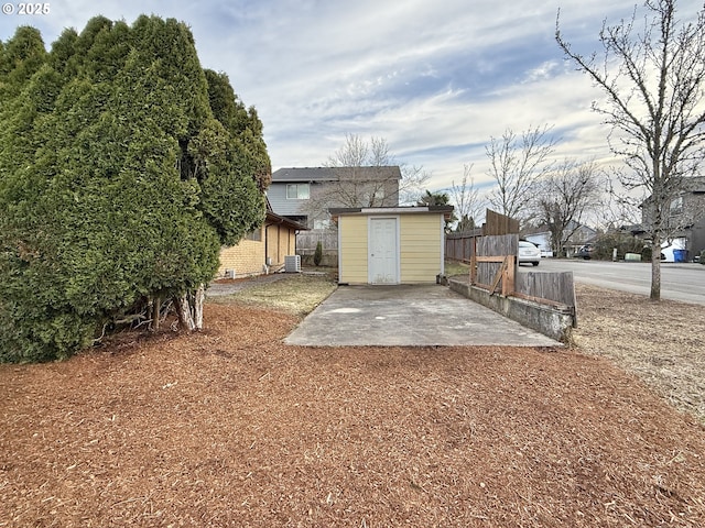 view of yard with an outbuilding, central AC unit, a storage unit, and fence