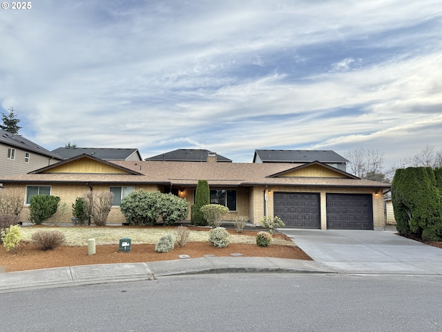 view of front of home featuring brick siding, solar panels, concrete driveway, and an attached garage