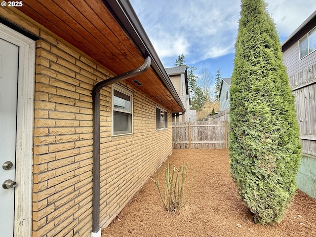 view of side of property with brick siding and fence