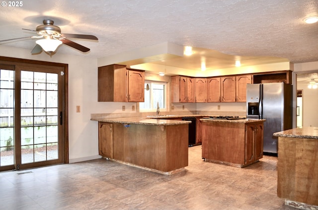 5207 NE 56th Way, Vancouver, WA 98661 - kitchen with stainless steel appliances, a peninsula, brown cabinets, a ceiling fan, and a textured ceiling