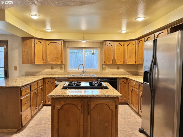 kitchen with stovetop, a sink, black dishwasher, stainless steel refrigerator with ice dispenser, and a center island