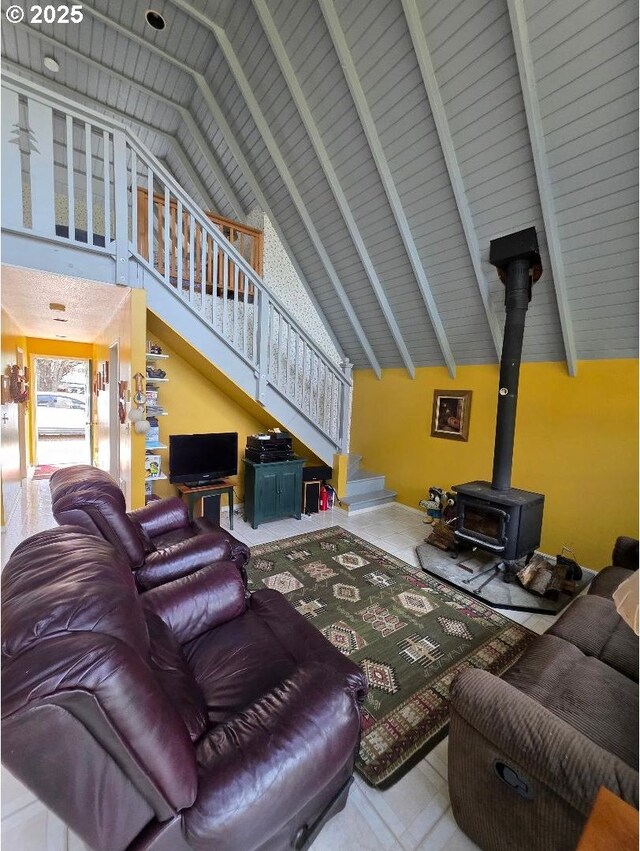 living room featuring beamed ceiling, stairway, a wood stove, and high vaulted ceiling