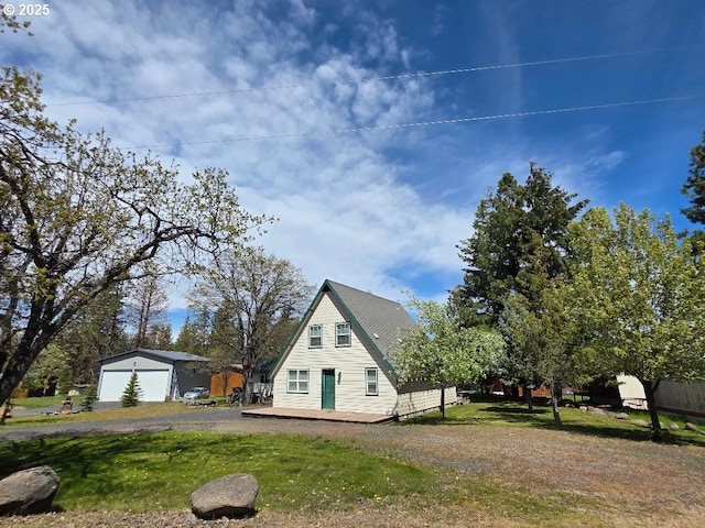 view of side of home with a detached garage, an outbuilding, a lawn, and driveway