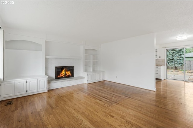 10700 NE 46th St, Vancouver, WA 98682 - unfurnished living room featuring light wood-type flooring, built in features, a fireplace, and baseboards