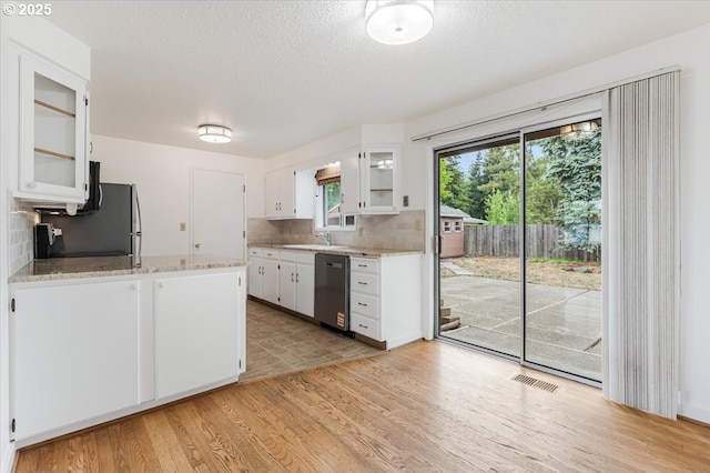 10700 NE 46th St, Vancouver, WA 98682 - kitchen with stainless steel dishwasher, light wood-style flooring, backsplash, white cabinets, and glass insert cabinets