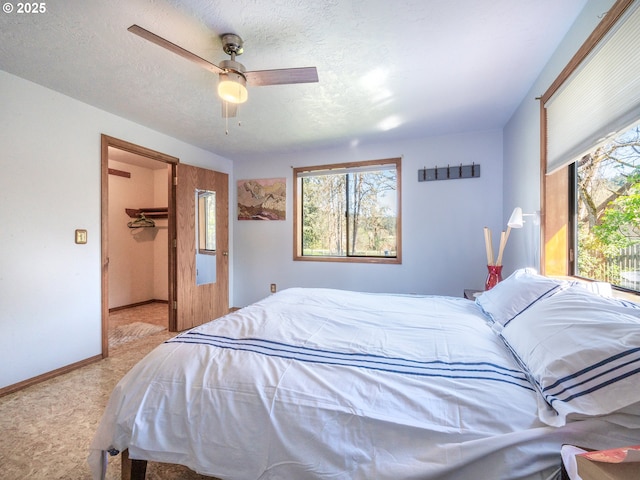 bedroom with a walk in closet, carpet flooring, baseboards, and ceiling fan