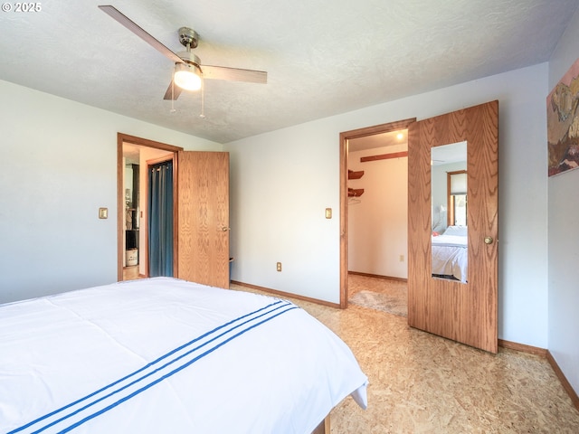 bedroom with a spacious closet, a textured ceiling, baseboards, and ceiling fan