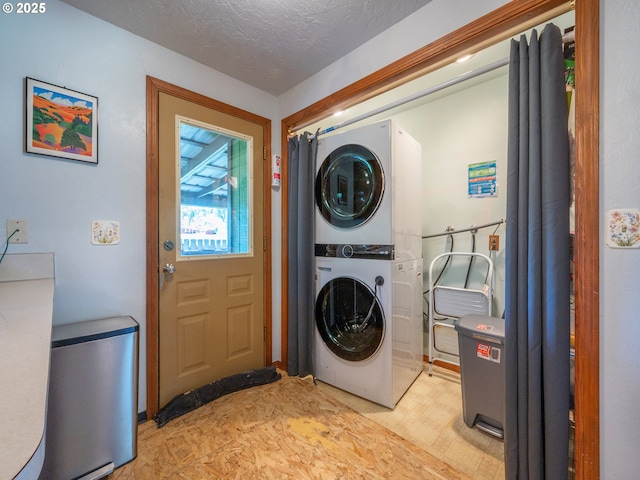 clothes washing area with light floors, stacked washing maching and dryer, a textured ceiling, and laundry area