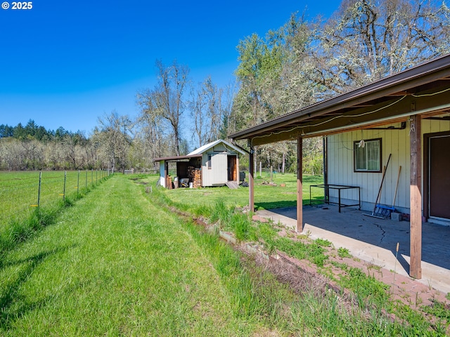 view of yard with a storage shed, a patio, fence, and an outdoor structure