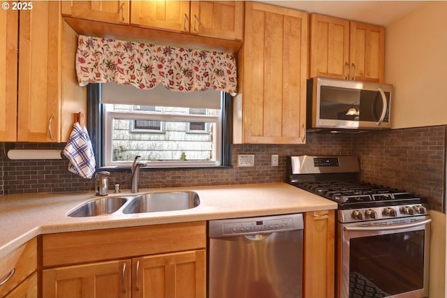 kitchen featuring appliances with stainless steel finishes, light countertops, a sink, and tasteful backsplash