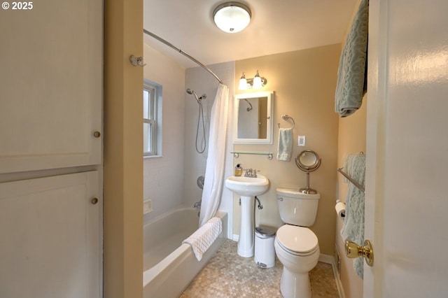 bathroom with shower / tub combo, a sink, toilet, and baseboards