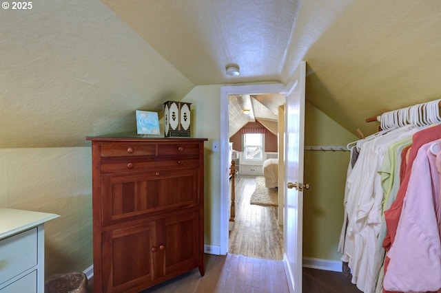 interior space featuring vaulted ceiling, baseboards, and wood finished floors