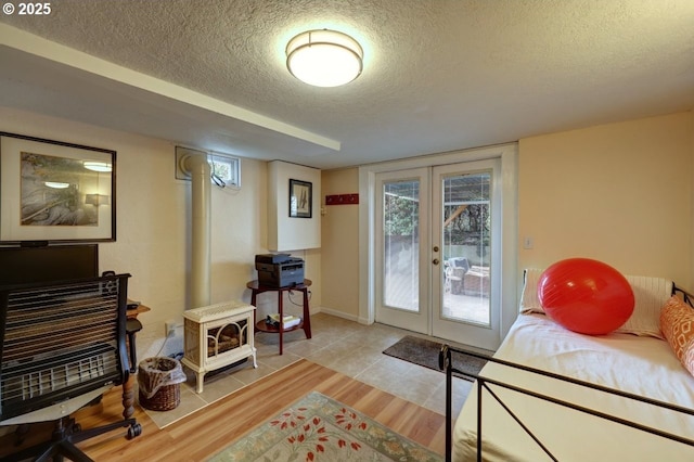 doorway featuring a textured ceiling, wood finished floors, french doors, a wealth of natural light, and a wood stove