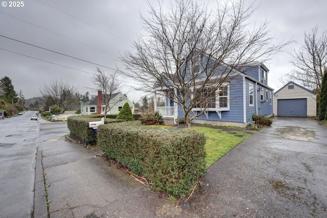 view of front of house featuring covered porch, aphalt driveway, an outdoor structure, and a detached garage