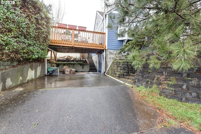 exterior space featuring aphalt driveway, a carport, and stairs