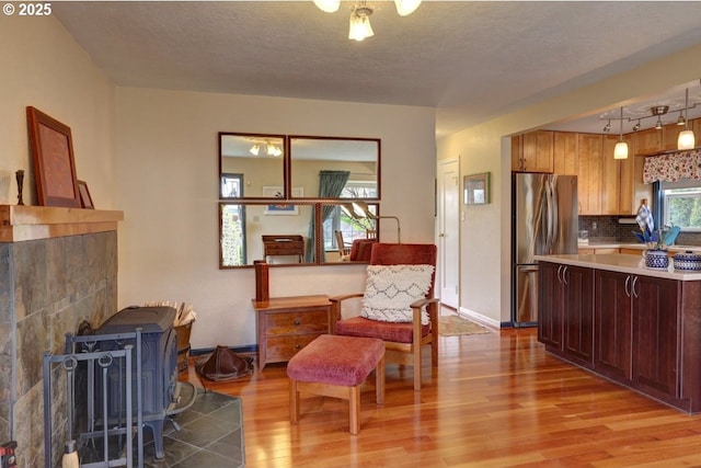 living area featuring baseboards, a textured ceiling, and light wood finished floors