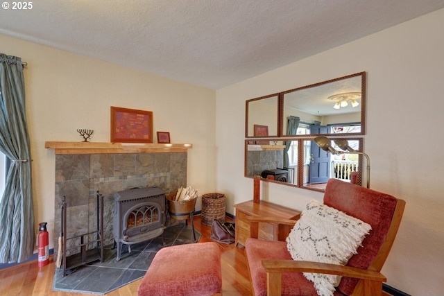 sitting room featuring a wood stove, a textured ceiling, and wood finished floors