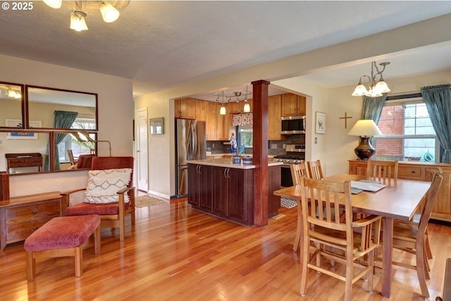 dining area featuring a textured ceiling, a wealth of natural light, light wood-style flooring, and a notable chandelier