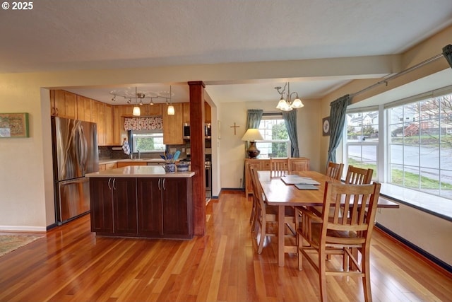 kitchen with a sink, light wood finished floors, a wealth of natural light, and freestanding refrigerator