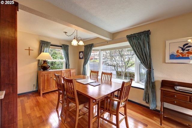 dining room with a chandelier, beam ceiling, baseboards, and light wood finished floors