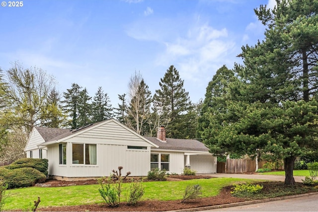 ranch-style house featuring a chimney, fence, concrete driveway, an attached garage, and a front yard