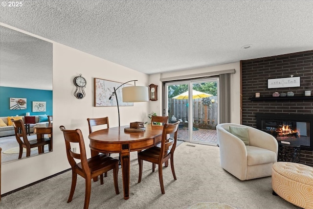 dining area featuring visible vents, baseboards, carpet floors, a fireplace, and a textured ceiling