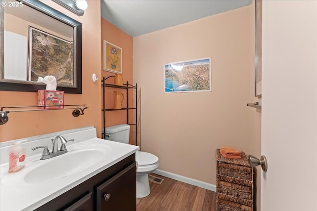 bathroom with visible vents, toilet, wood finished floors, baseboards, and vanity