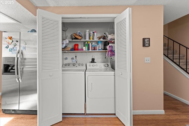 laundry room featuring light wood-style floors, washing machine and dryer, laundry area, and a textured ceiling