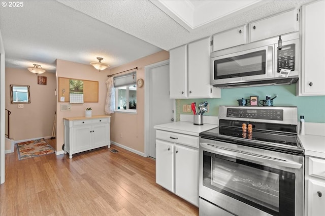 kitchen featuring white cabinetry, light countertops, light wood-style flooring, and appliances with stainless steel finishes