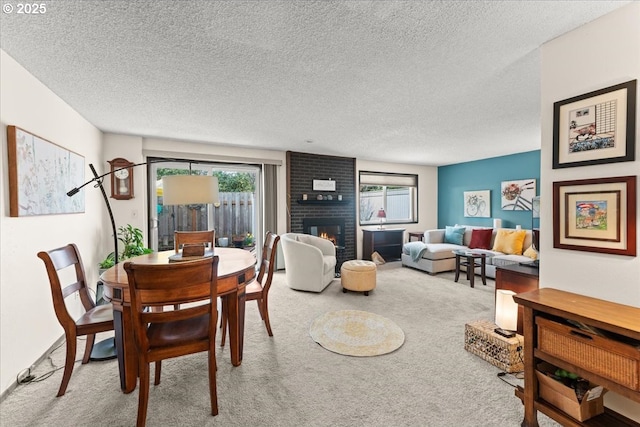 dining space with a brick fireplace, carpet flooring, and a textured ceiling