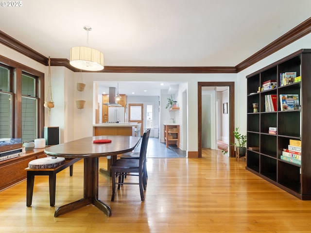 dining room with ornamental molding and light wood-style floors